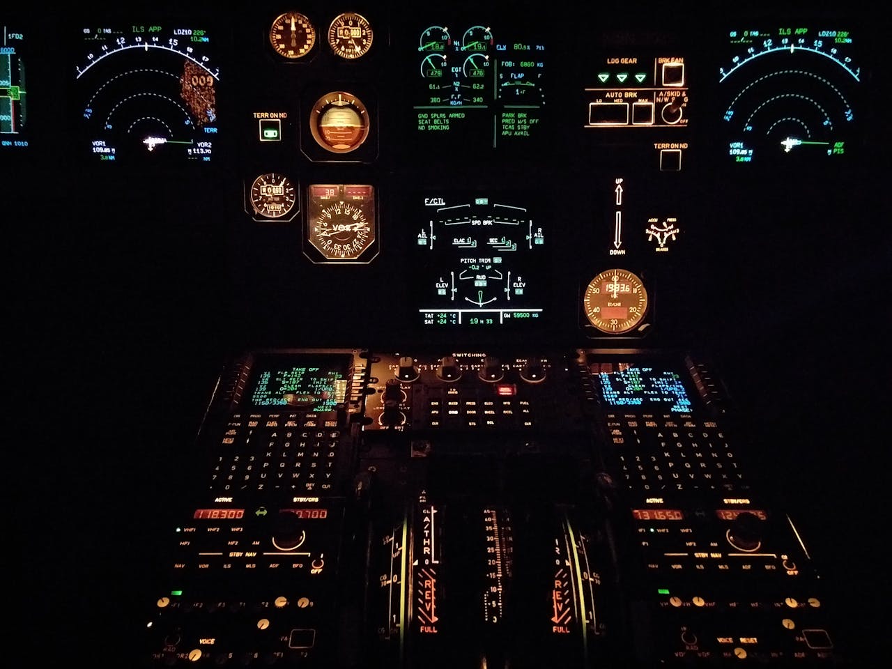 Close-up view of an aircraft cockpit illuminated at night with various gauges and instruments.
